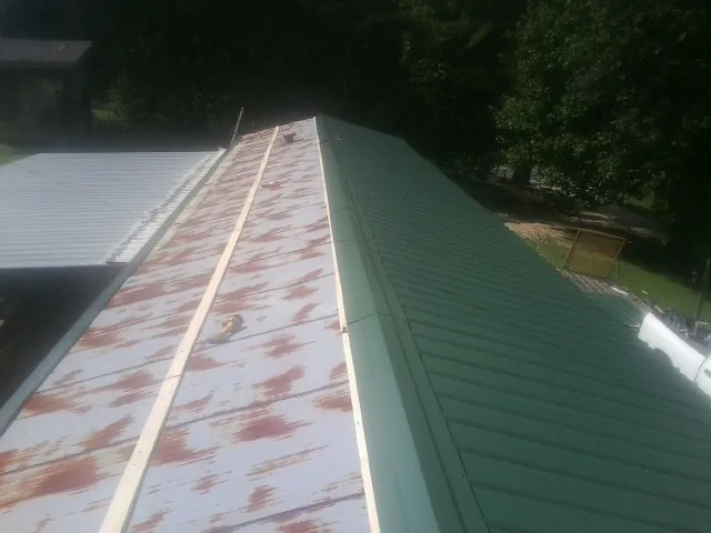 Old rusted panels beside newly installed green metal roofing — Wind Damage Roof Repair by Roofing Brothers in Endicott