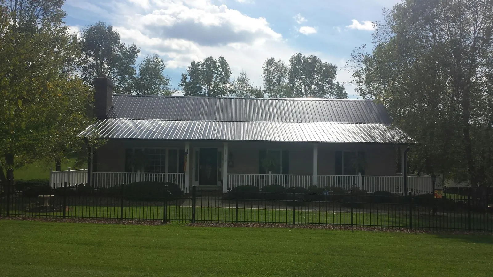 Gray metal roof on a brick ranch with a full width front porch — Gutter Guard Installation work by our crew in Endicott